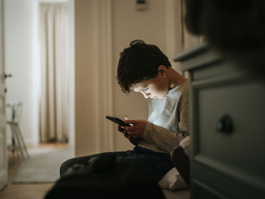 Junge beugt sich über sein Smartphone.