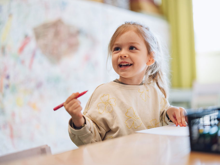 Ein kleines Mädchen mit einem Stift in der Hand.