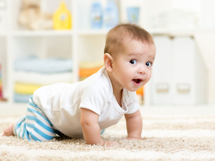 Baby krabbelt auf dem Teppich.