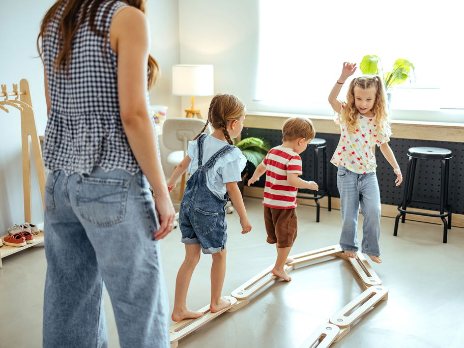 Drei Kinder spielen mit einer Frau.