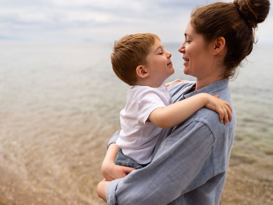 Mutter hält Sohn am Strand im Arm