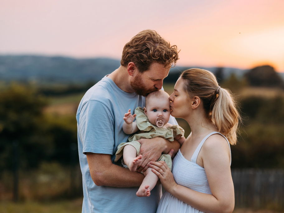 Mama und Papa mit Baby im Sonnenuntergang.