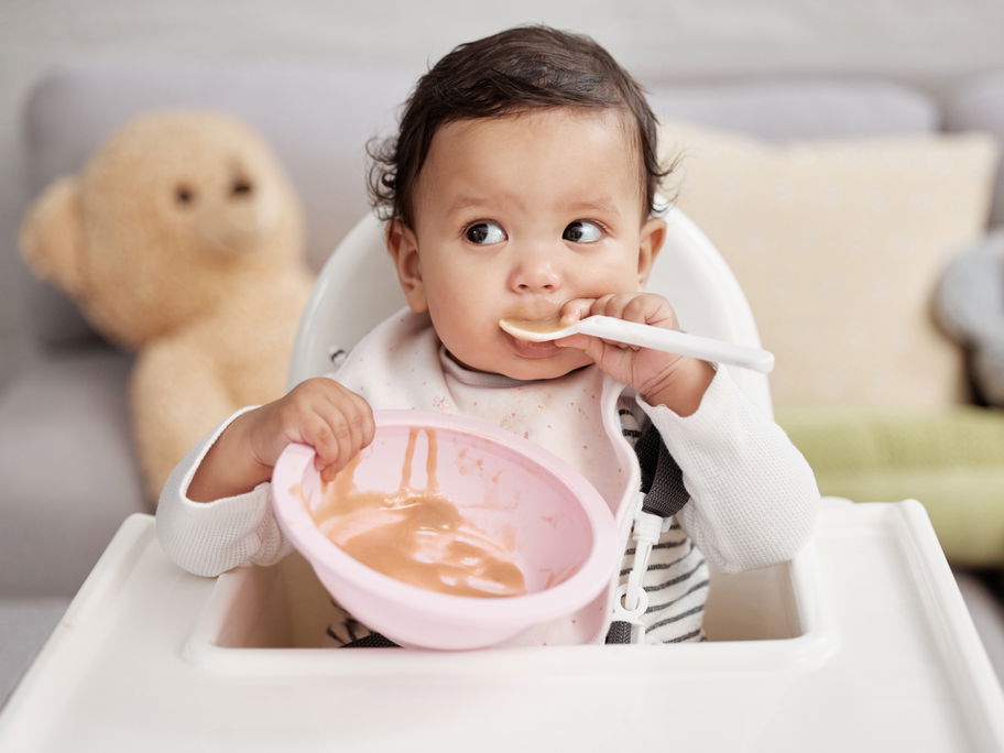 Baby löffelt Obstbrei.