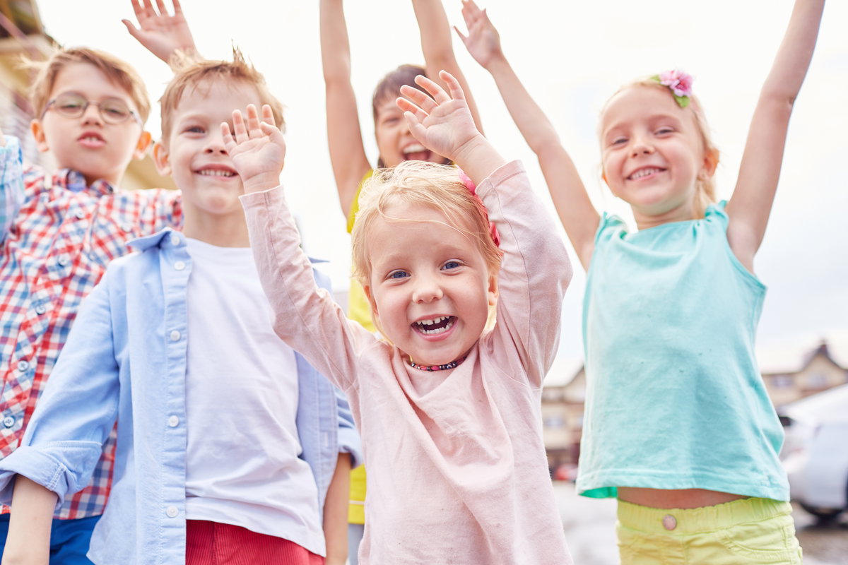 Lachende Kinder mit erhobenen Armen.