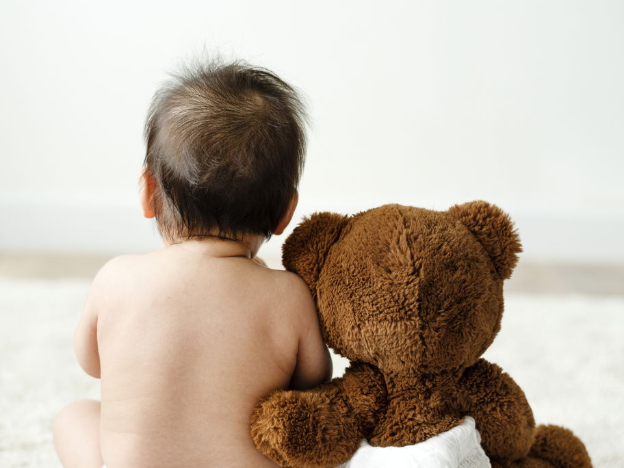 Baby und Kuschelbär mit Windeln.