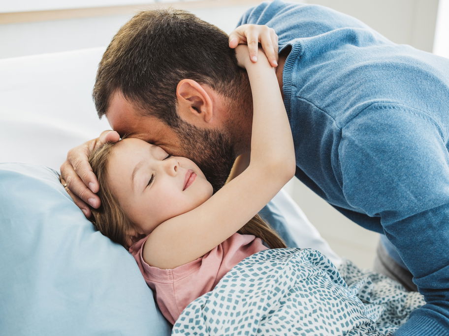 Kind umarmt seinen Vater beim Ins-Bett-Gehen.