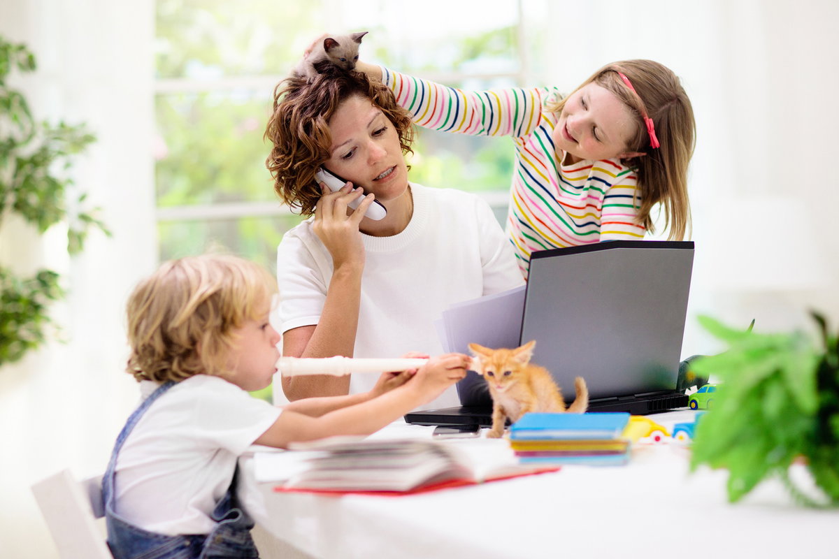 Mutter am Laptop wird von zwei Kindern genervt.
