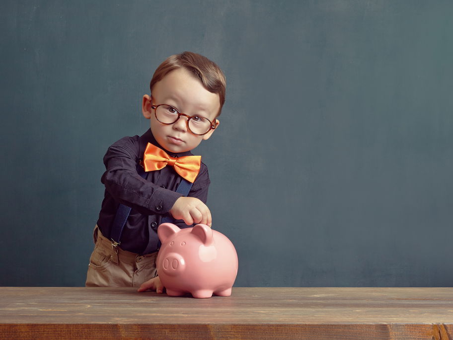 Junge steckt Geld in sein Sparschwein.