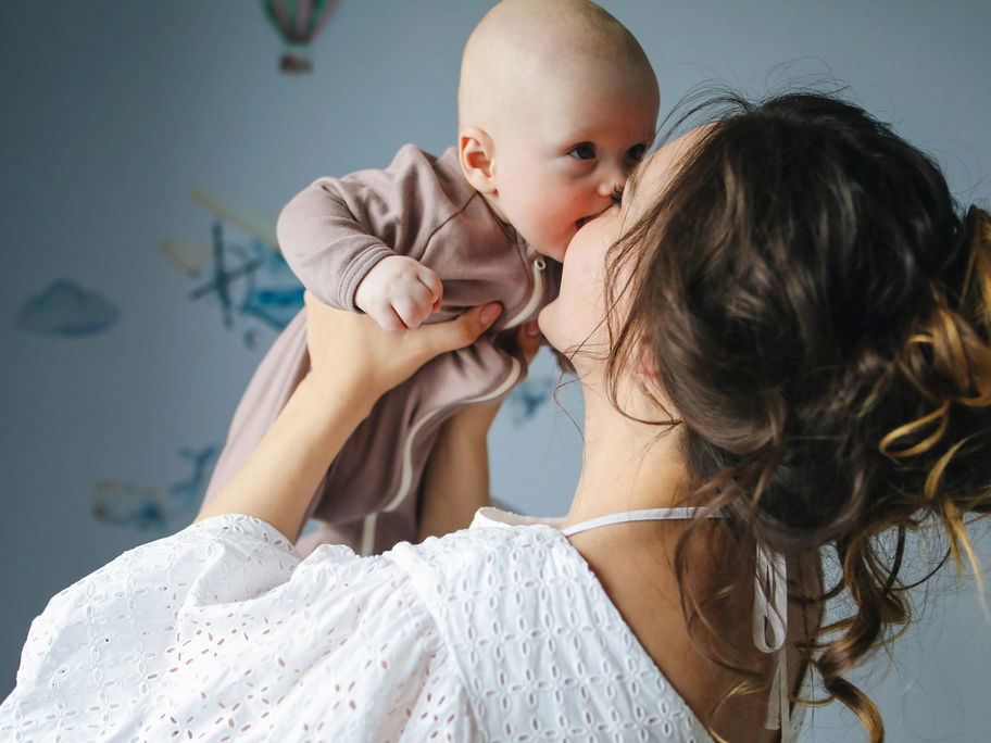 Eine Mama hebt ihr Baby hoch.