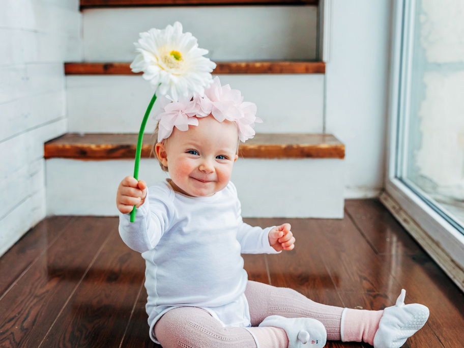 Ein kleines Baby, das eine Blume hält.
