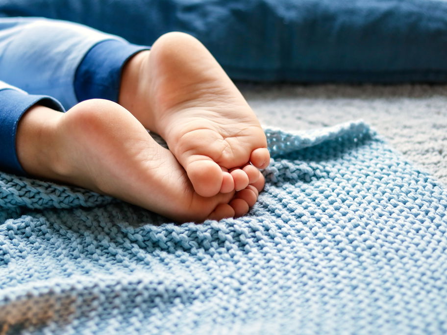 Nahaufnahme von barfüßigen Kinderfüßen auf blauer Decke