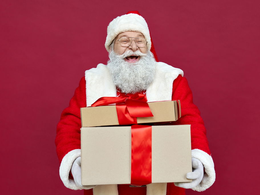 Ein Nikolaus mit Geschenken im Arm lacht aus vollem Herzen.