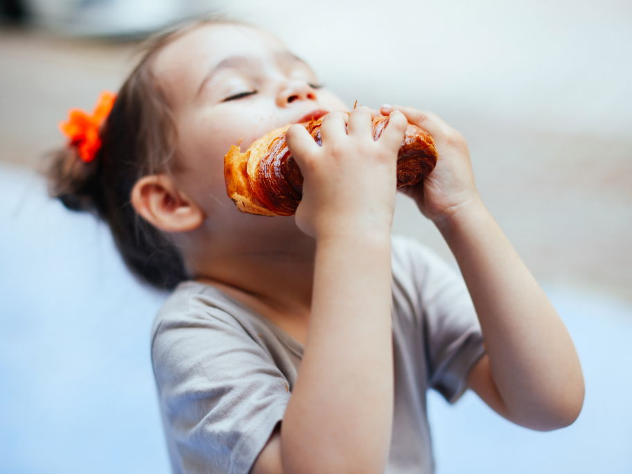 Ein Mädchen beißt in ein Croissant.