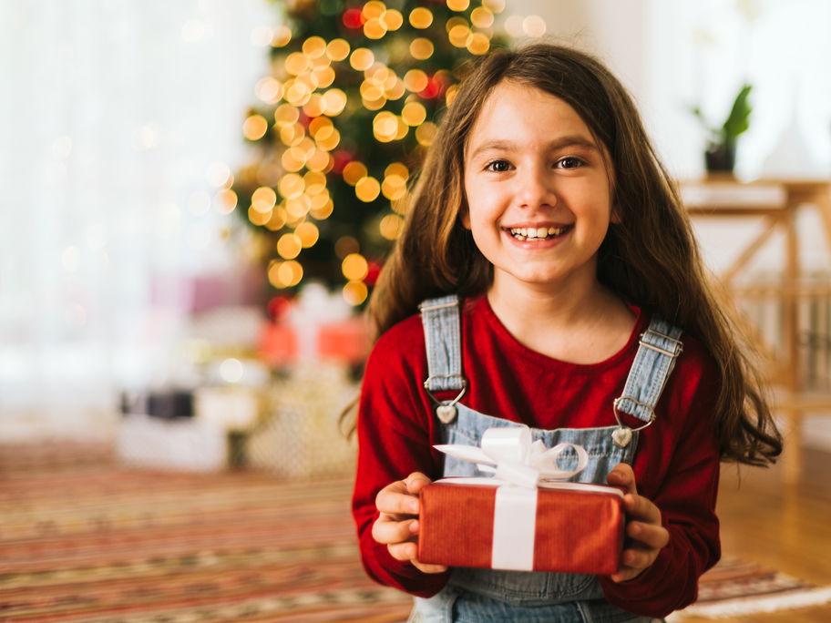 Lachendes Mädchen übergibt Weihnachtsgeschenk.
