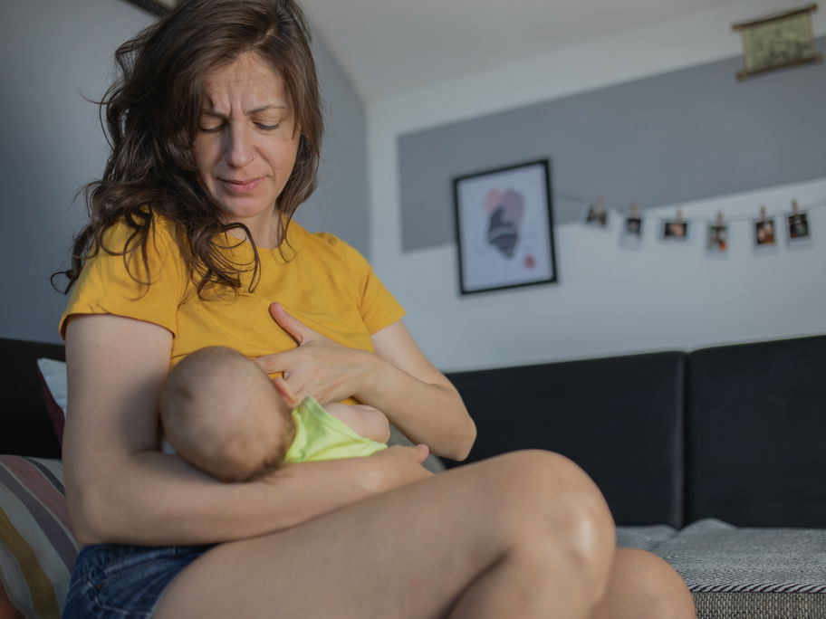 Mutter legt ihr Baby zum Stillen an.