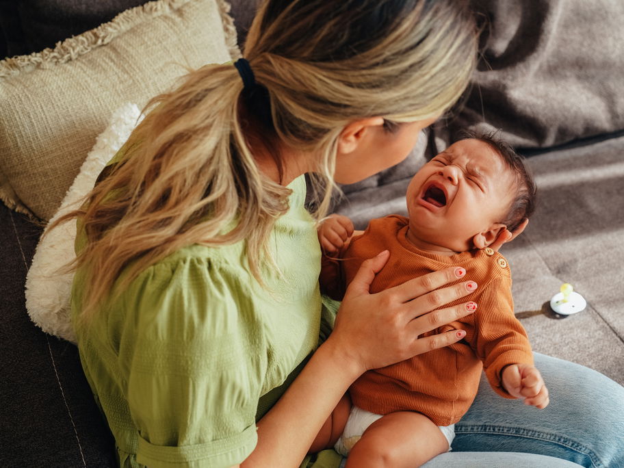 Mama versucht, ihr Neugeborenes zu beruhigen.