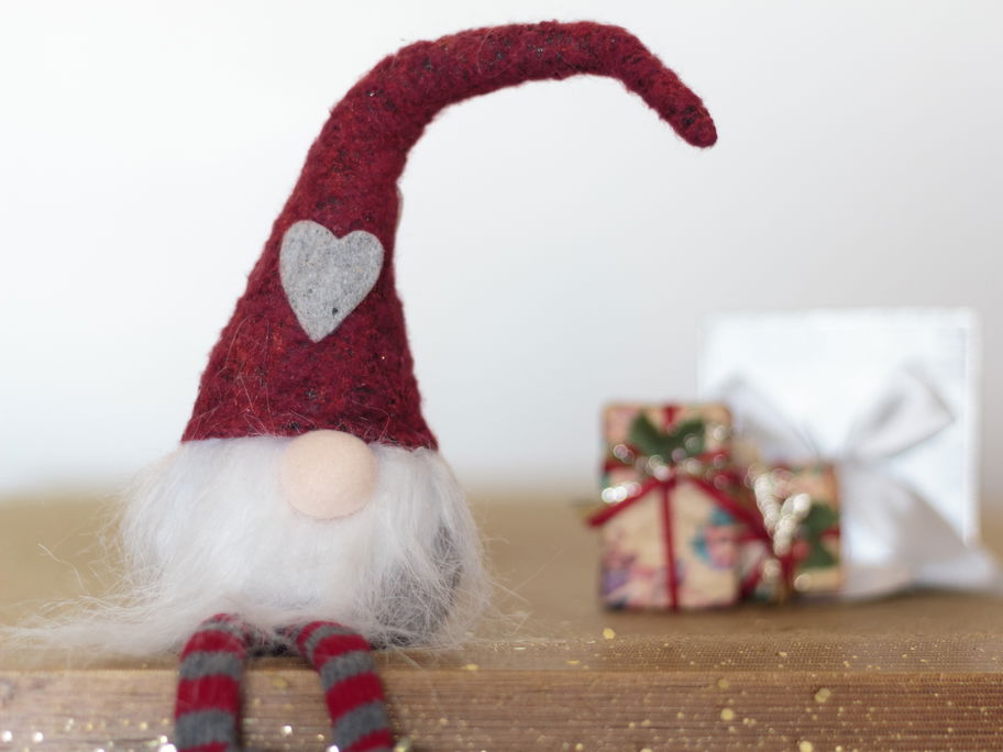 Wichtel sitzt vor Geschenken.