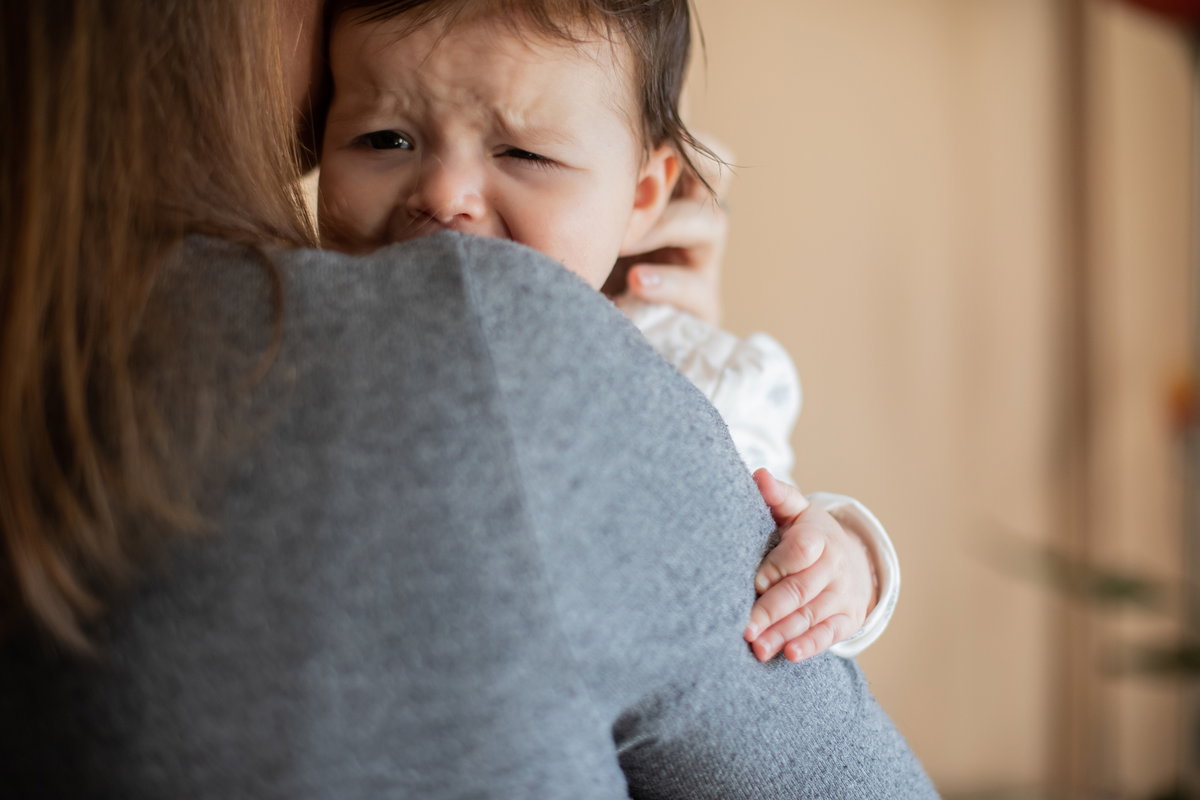 Baby weint auf Mamas Arm.