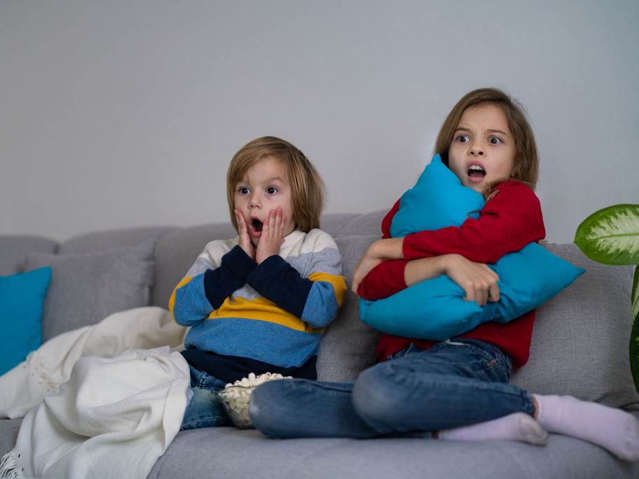 Zwei kleine Kinder fürchten sich vor dem Fernseher.