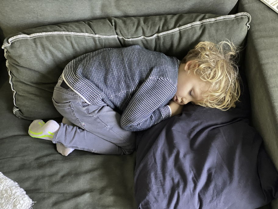 Kind hält Mittagsschlaf auf dem Sofa.
