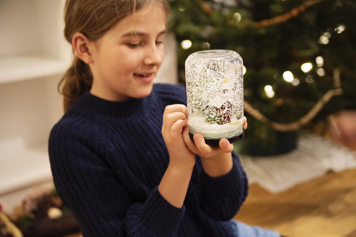 Mädchen hält selbstgebastelte Schneekugel in der Hand.
