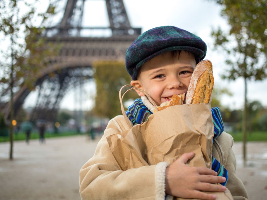 Ein Kind in Frankreich mit Baguettes in der Hand