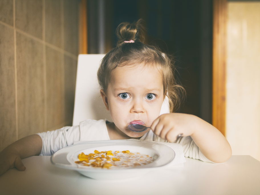Kleines Mädchen isst Müsli.