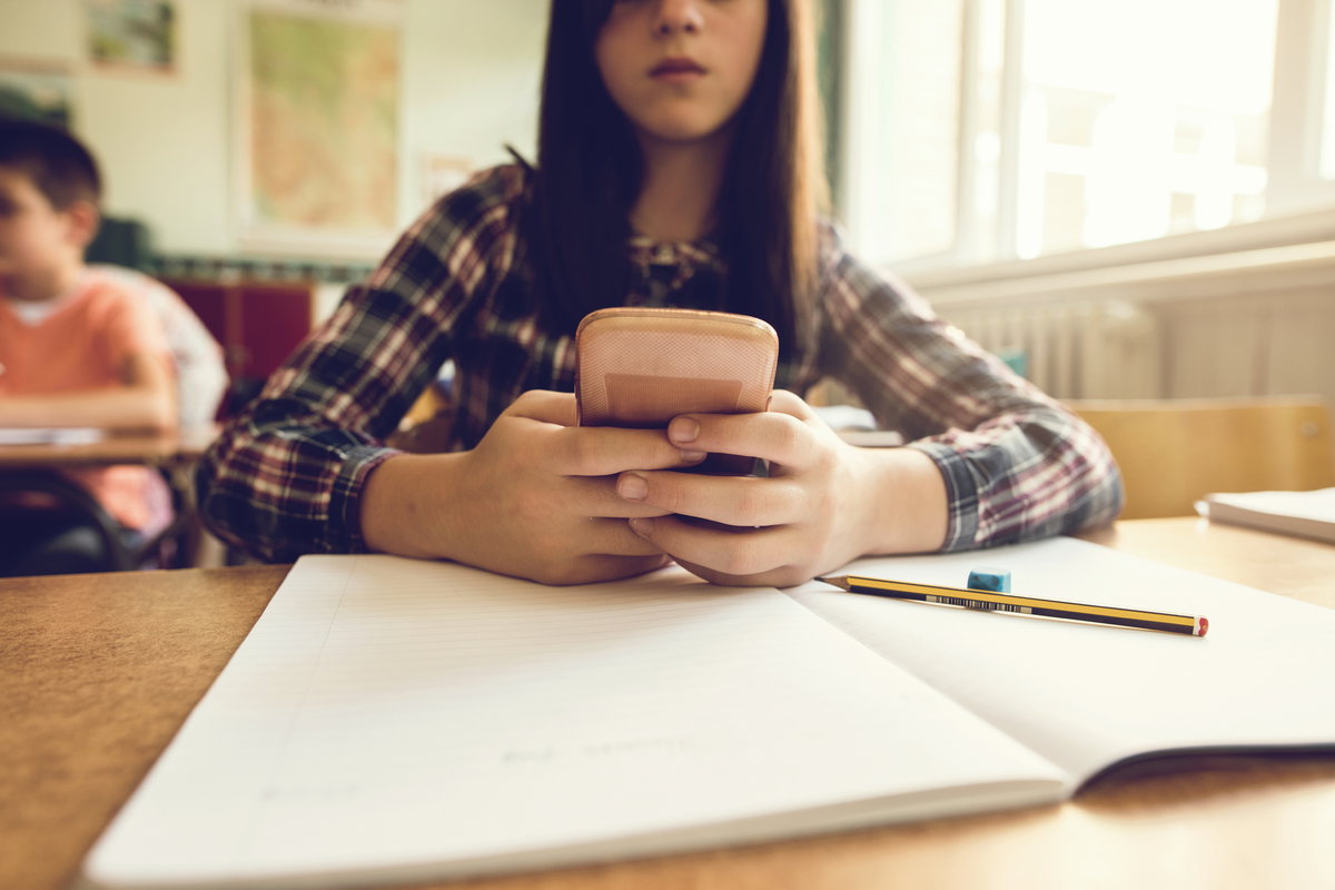 Schülerin mit Handy im Klassenzimmer