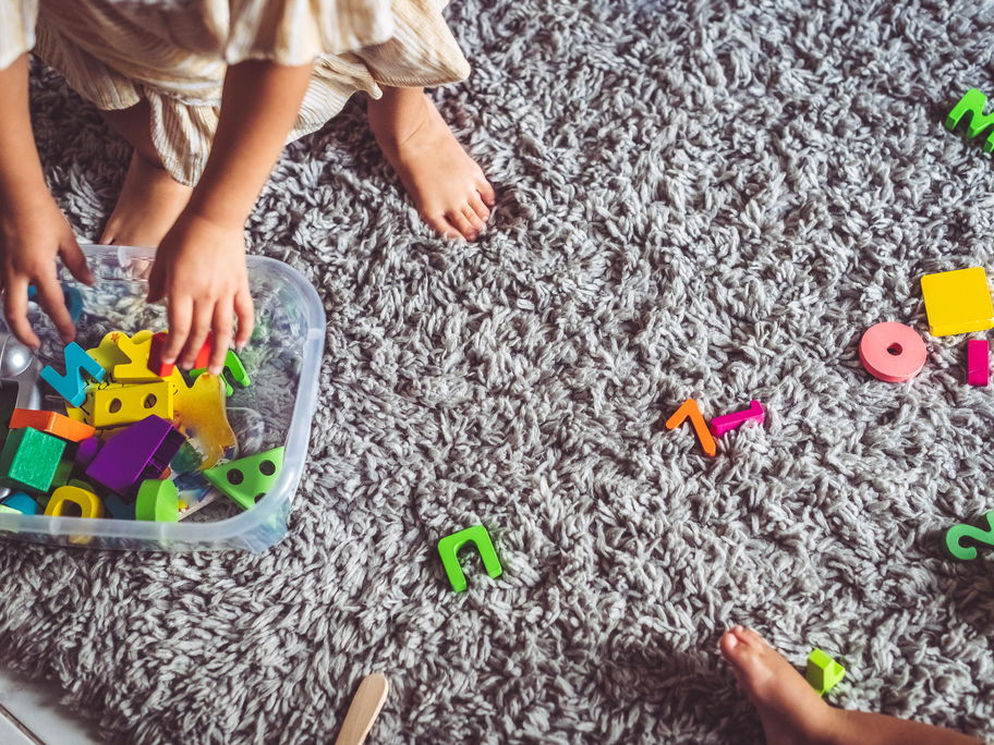 Kind räumt Spielsachen auf.