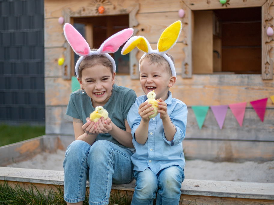 Zwei Kinder mit Osterhasenohren und einem Küken in der Hand