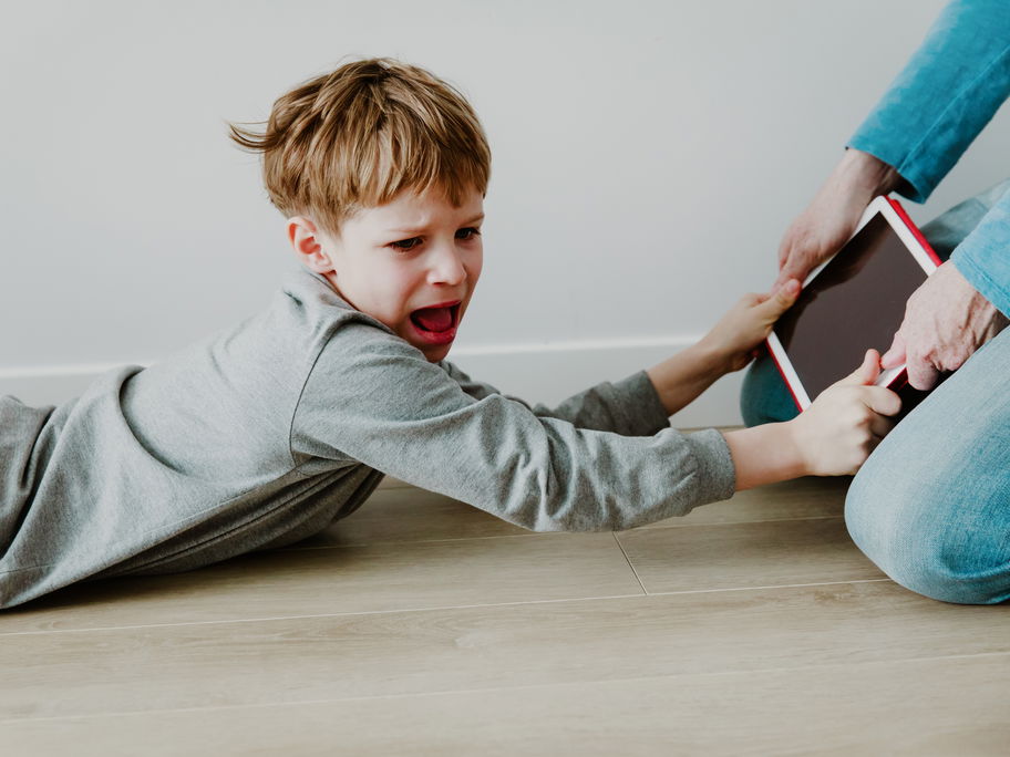 Junge hält schreiend das Tablet fest.