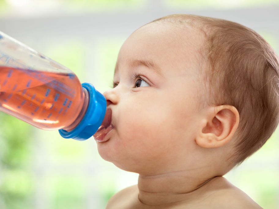 Baby trinkt Tee aus Nuckelflasche.