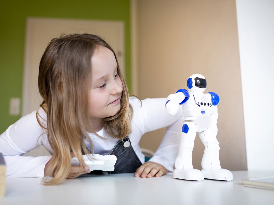 Mädchen spielt mit kleinem Roboter.