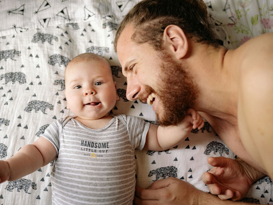 Ein Vater kuschelt mit seinem neugeborenen Baby.