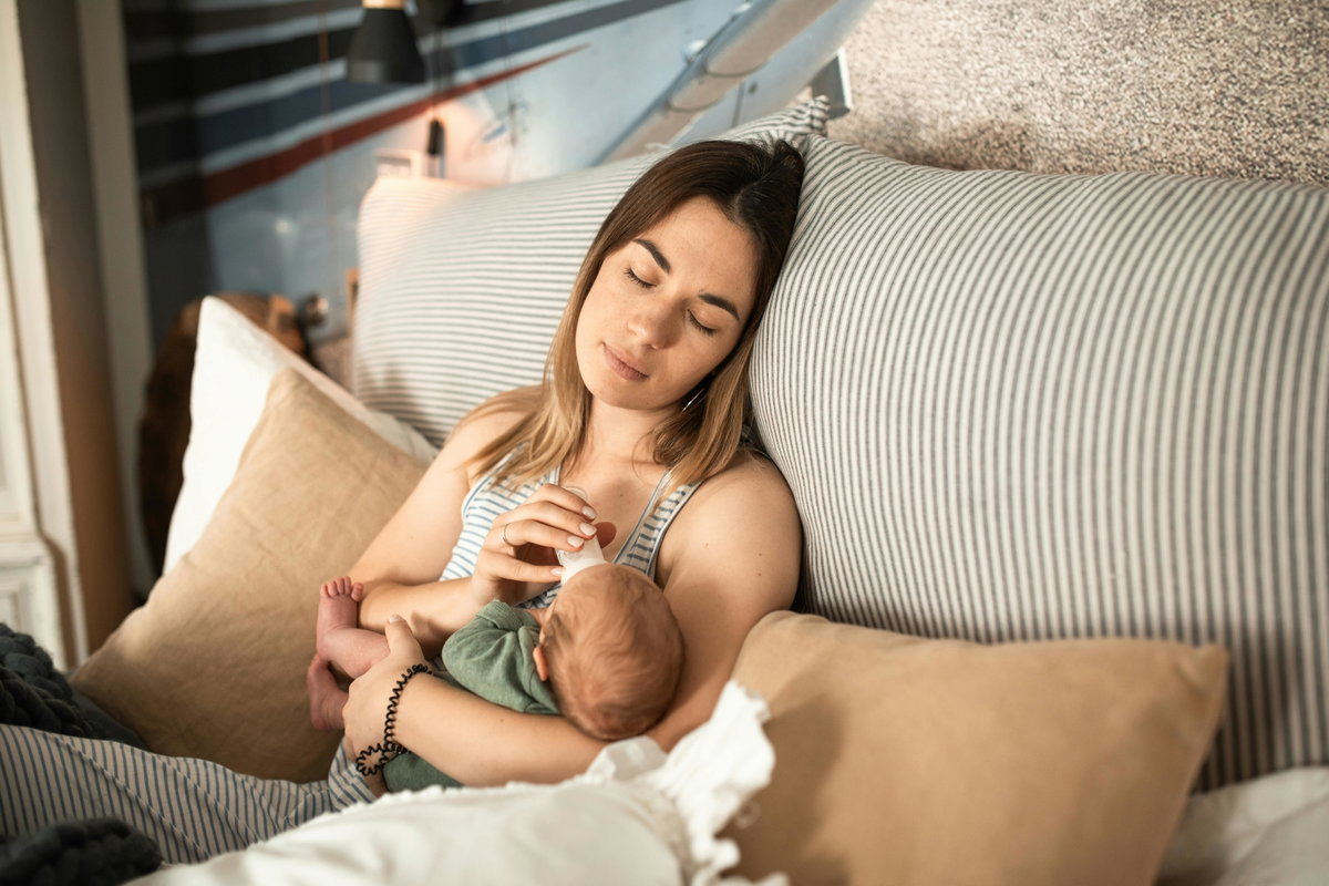 Müde Mama füttert ihr Baby mit der Flasche.