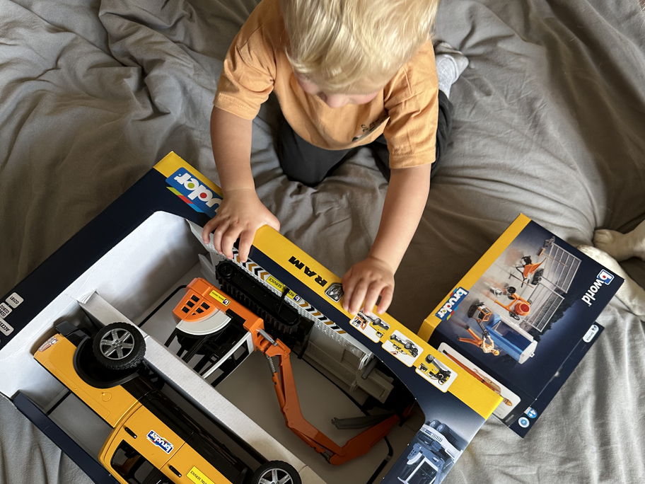 Victorias Sohn packt das Paket von Bruder Spielwaren aus.