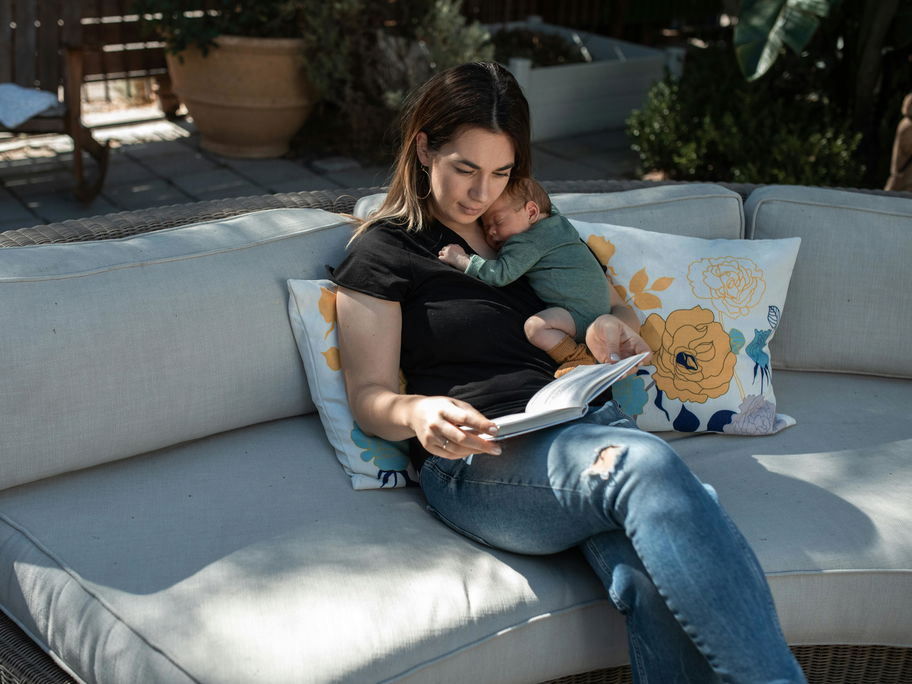 Mama sitzt mit Baby draußen auf Sofa.
