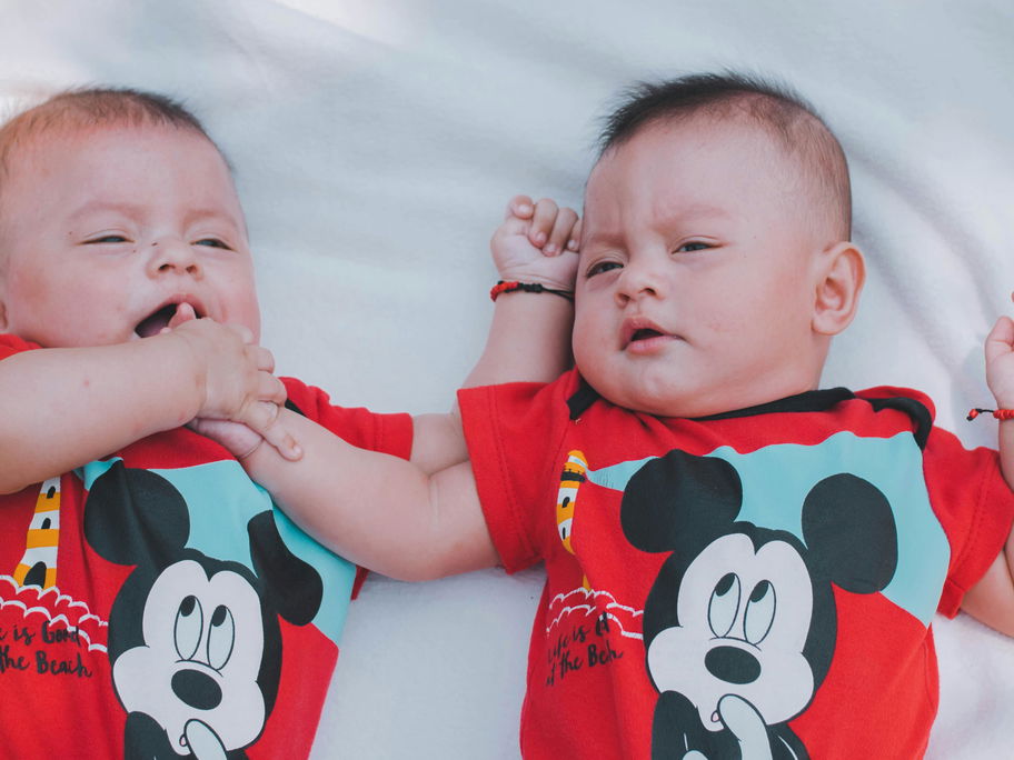 Zwillingsbabys mit Micky-Maus-Body