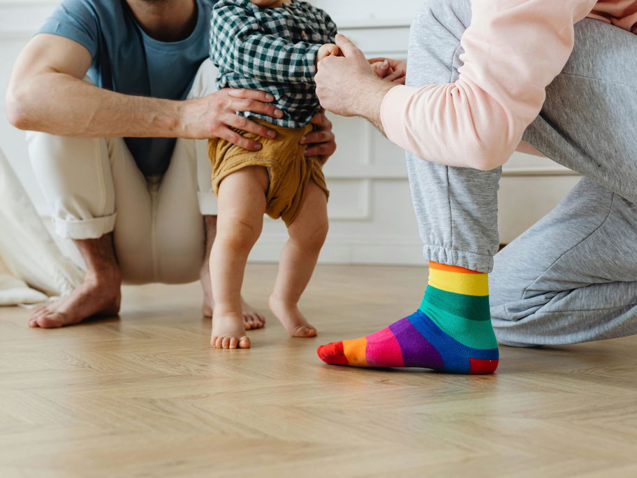Baby läuft barfuß mit Hilfe von einem zum anderen.
