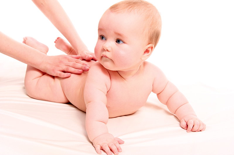Ein Baby wird am Rücken massiert.