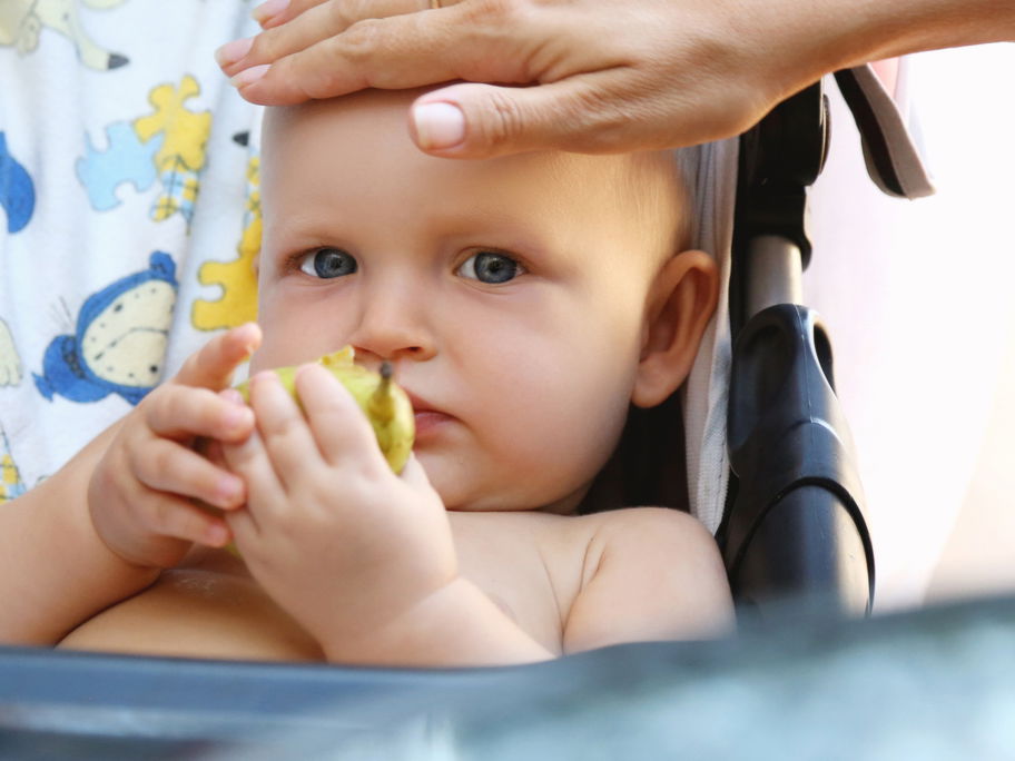 Eine Mutter fühlt die Stirn ihres Babys.
