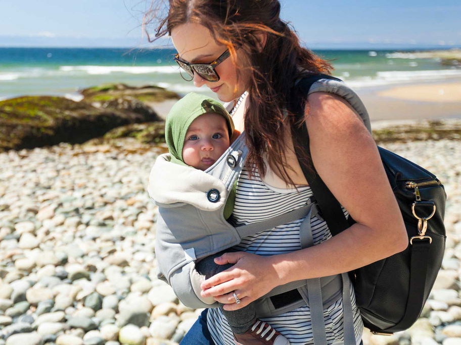 Mutter mit Baby im Tragesitz am Strand