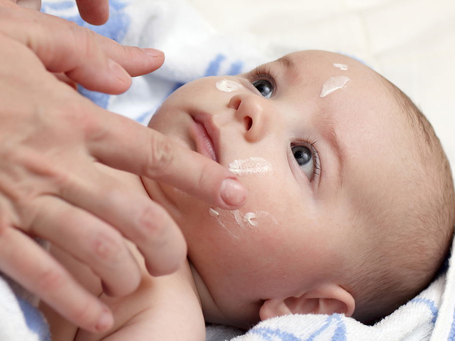 Babys Gesicht wird eingecremt.