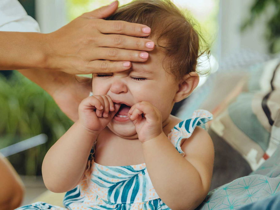Mutter fühlt heiße Stirn eines schreienden Babys.