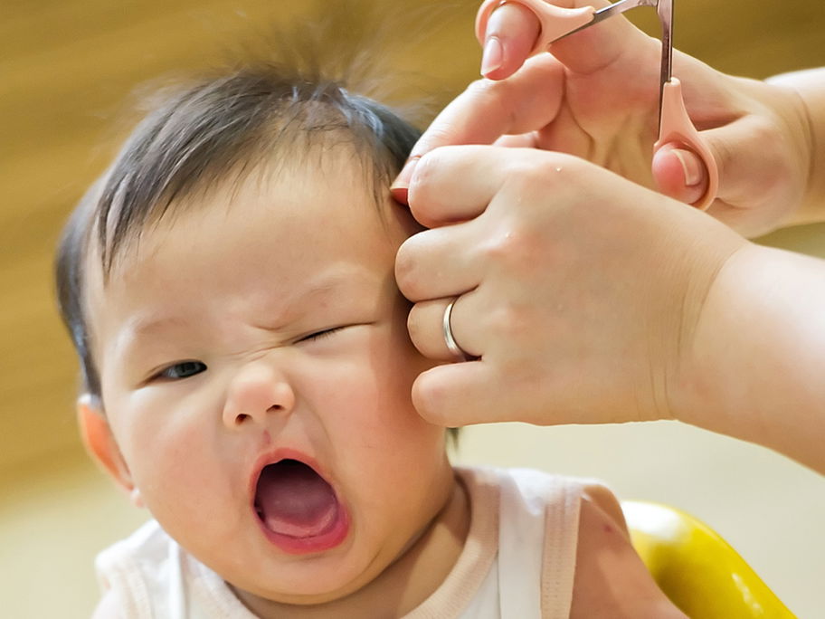 Babys sind nicht immer begeistert, wenn man ihnen die Haare schneiden möchte.