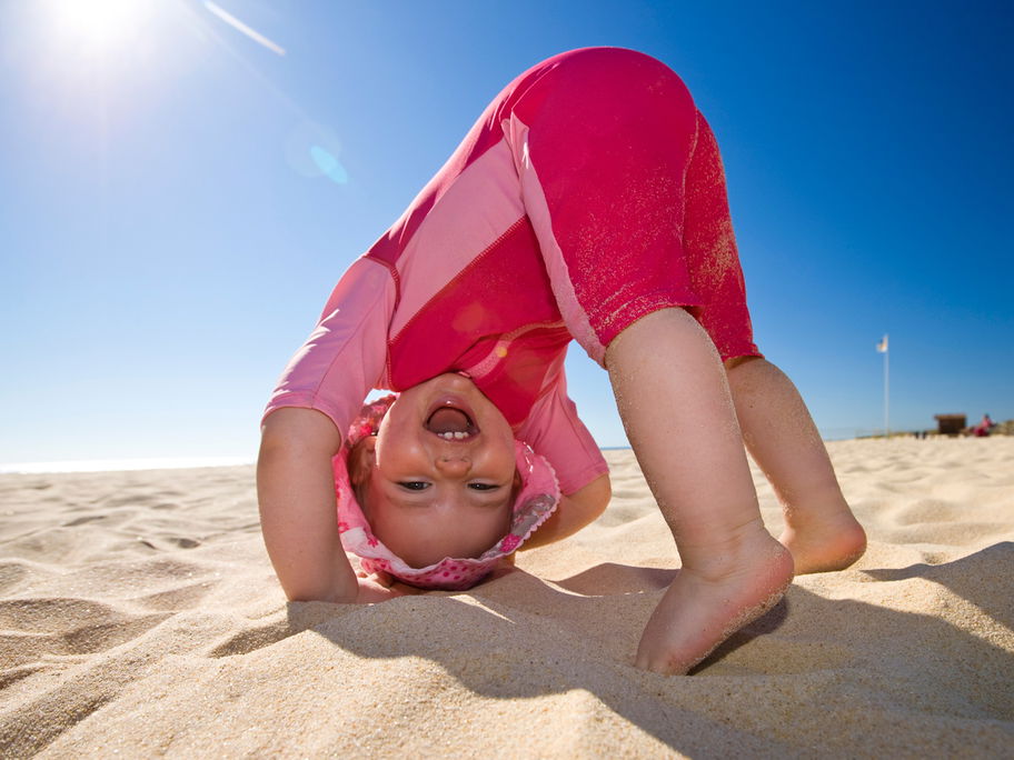 Ein Baby spielt in UV-Kleidung am Strand.