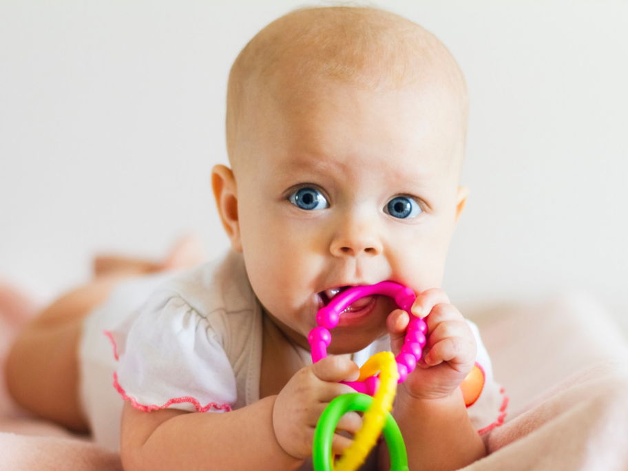 Baby liegt auf dem Bauch und kaum am Beißring.