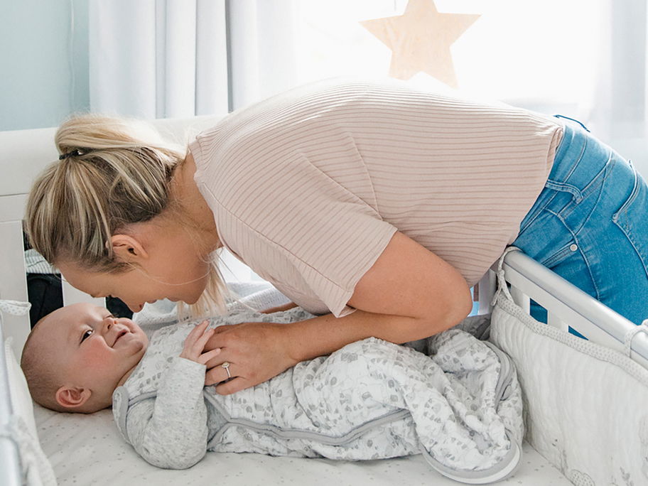 Eine Mama bringt ihr Baby ins Bett.