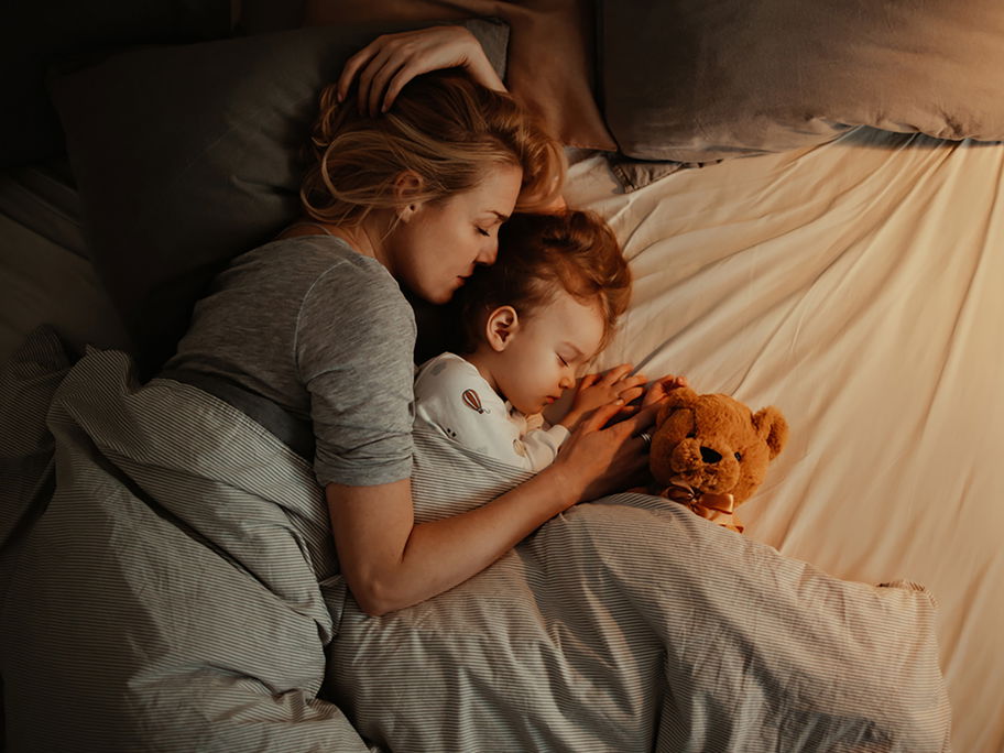 Mutter liegt mit kleinem Kind im Bett.