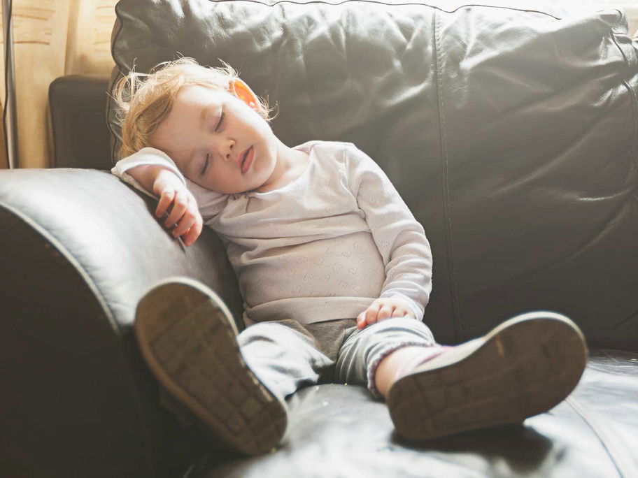 Ein Kleinkind, das auf dem Sofa einschläft.